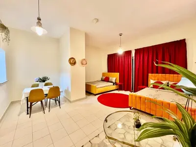 a living room with a table and a red curtain at Sandoval Gardens JVC in Dubai