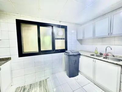a kitchen with a trash can and a window at Mina Road AL Thayer in Dubai
