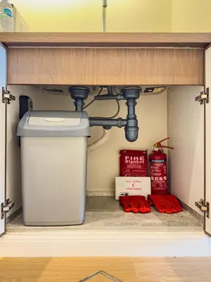 a kitchen under a sink with a trash can at Classy Studio in the Heart of Greens in Dubai