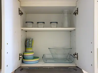 a cupboard with bowls and other dishes in it at Classy Studio in the Heart of Greens in Dubai
