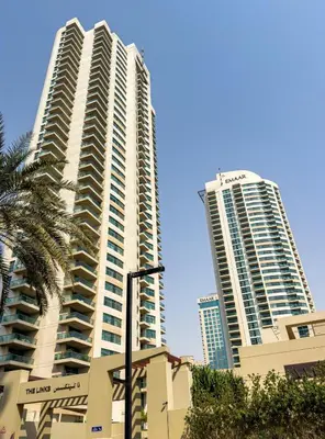 two tall buildings in a city with a palm tree at Classy Studio in the Heart of Greens in Dubai