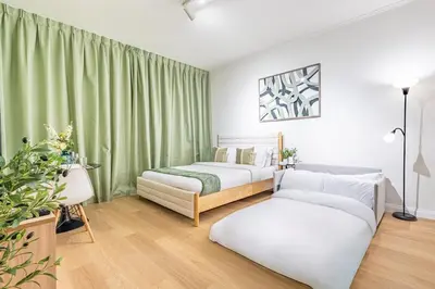 two beds in a room with green curtains and a couch at Classy Studio in the Heart of Greens in Dubai
