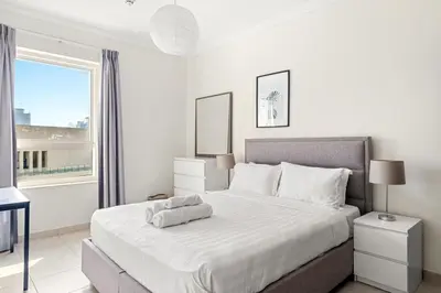 a white bedroom with a large bed and a window at Elegant 1-Bedroom Apartment in Dubai Marina in Dubai