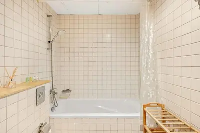 a white tiled bathroom with a tub and a shower at Elegant 1-Bedroom Apartment in Dubai Marina in Dubai