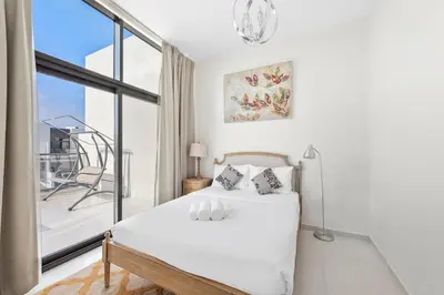a white bedroom with a bed and a large window at Elegant 3BR Villa with Access to Pool & Gym in Dubai