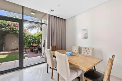 a dining room with a wooden table and chairs at Elegant 3BR Villa with Access to Pool & Gym in Dubai