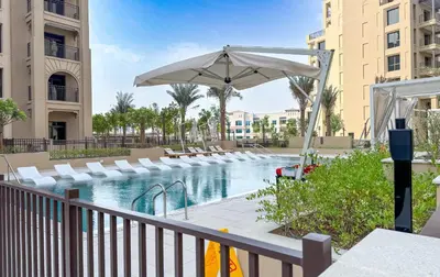 a swimming pool with an umbrella and lounge chairs at Modern 1BR Steps from Burj AlArab Madinat Jumeirah By AYA Boutique in Dubai