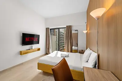 a hotel room with a bed and a table and a tv at Charming Studio with Pool, Gym, Kid's playground in Dubai