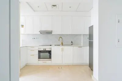 a white kitchen with white cabinets and a sink at Chic Urban Loft SkyGardens DIFC, Dubai in Dubai