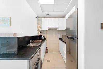 a kitchen with white cabinets and a black counter top at Spacious Studio - 10 min drive to Burj Khalifa in Dubai