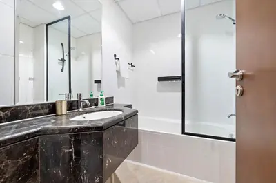 a bathroom with a sink and a mirror and a tub at Spacious Studio - 10 min drive to Burj Khalifa in Dubai
