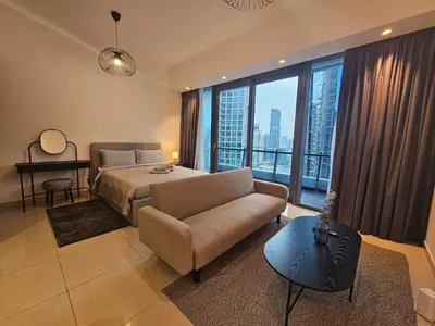 a bedroom with a bed and a couch and a window at Dubai Silverene Tower with large balcony and high floor Marina views in Dubai