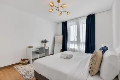 a bedroom with a white bed and a chandelier at Stylish 1BR Port De La Mer Escape with Beach Access in Dubai