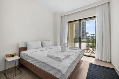 a white bedroom with a bed and a balcony at Spacious 1 bedroom in creek beach-Huge Balcony in Dubai
