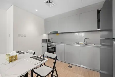 a kitchen with white cabinets and a table with chairs at Spacious 1 bedroom in creek beach-Huge Balcony in Dubai