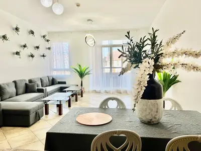 a living room with a table with a vase of flowers at Motor City Shakespeare Circus in Dubai