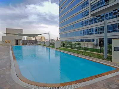 a large blue swimming pool in front of a building at Modern Studio in Skycourts, Near Dubai Outlet Mall in Dubai