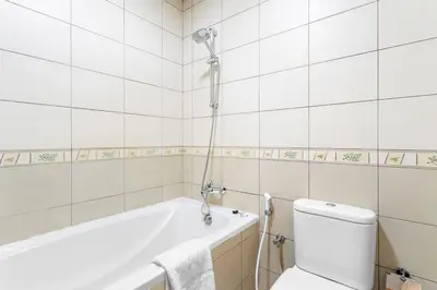 a white bathroom with a tub and a toilet at Modern Studio in Skycourts, Near Dubai Outlet Mall in Dubai