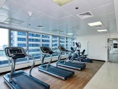a gym with several cardio machines in a building at Modern Studio in Skycourts, Near Dubai Outlet Mall in Dubai