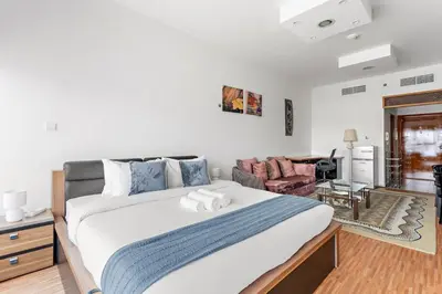 a bedroom with a large bed and a couch at Modern Studio in Skycourts, Near Dubai Outlet Mall in Dubai