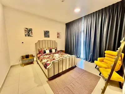 a bedroom with a bed and a yellow chair at Jaddaf Pool Gym Parking in Dubai