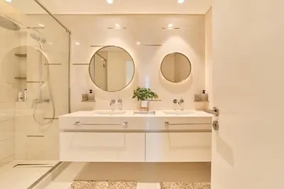 a white bathroom with a sink and two mirrors at Luxury 2BR in Beach Vista With Stunning Palm Views in Dubai