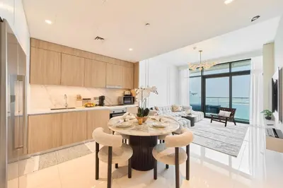 a kitchen and living room with a table and chairs at Luxury 2BR in Beach Vista With Stunning Palm Views in Dubai