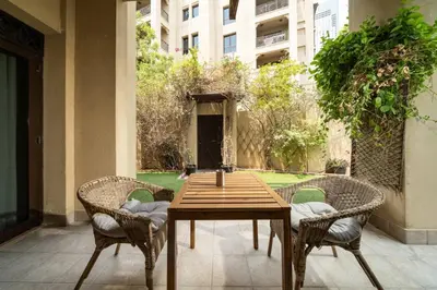 a wooden table and chairs on a patio at Stylish Old Town 1 Bed Plus Maids with Private Garden in Dubai