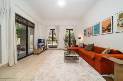a living room with a couch and a tv at Stylish Old Town 1 Bed Plus Maids with Private Garden in Dubai