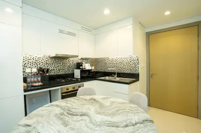 a kitchen with white cabinets and a table with chairs at High-Floor 2BR - Aykon City 2BR in Business Bay in Dubai