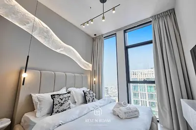 a bedroom with a bed and a large window at Brand New 1BR Near Parks and Mall JVC in Dubai