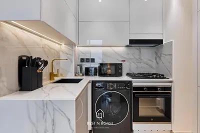a white kitchen with a stove and a dishwasher at Brand New 1BR Near Parks and Mall JVC in Dubai