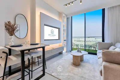 a living room with a table and a couch at High Floor 1BR - Near Parks and Mall - JVC in Dubai