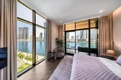 a bedroom with a large bed and large windows at Peninsula Five 3BD Duplex with Lake view, For 9 in Dubai