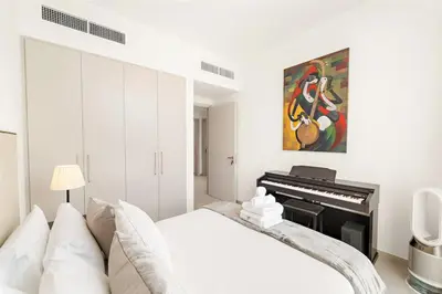 a bedroom with a white bed and a piano at Spacious 4BR Villa with Private Garden & Patio in Nadd Shubayḩ