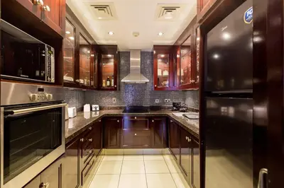 a kitchen with wooden cabinets and a stove top oven at Oasis in the heart of Downtown in Dubai