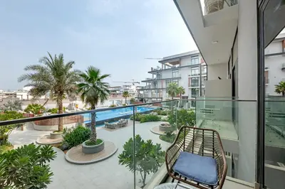 a balcony with a chair and a swimming pool at Waves - Modern JVC Studio with Balcony in Dubai