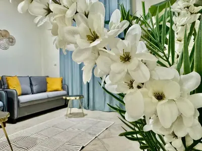 a vase of white flowers in a living room at Motor City Norton Court Parking Pool in Dubai