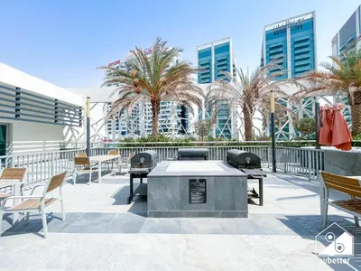 a patio with tables and chairs and palm trees at High-End Studio l Pool & Gym Included in Dubai