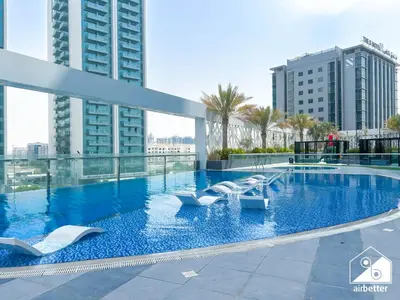 a large swimming pool with white chairs in a building at High-End Studio l Pool & Gym Included in Dubai