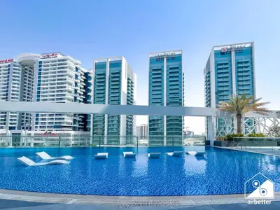 a large swimming pool in front of tall buildings at High-End Studio l Pool & Gym Included in Dubai