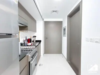 a white kitchen with a stove and a hallway at High-End Studio l Pool & Gym Included in Dubai