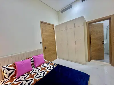 a bedroom with a bed with pink and purple pillows at Karama Palace Home in Dubai