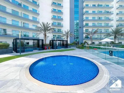 a large swimming pool in front of a building at Your Fav Studio Getaway l Pool, Gym & Parking! in Dubai