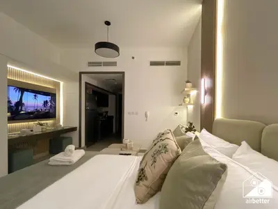 a bedroom with a white bed and a television at Your Fav Studio Getaway l Pool, Gym & Parking! in Dubai