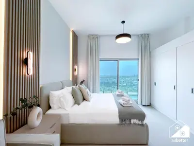 a bedroom with a large bed and a large window at Your Fav Studio Getaway l Pool, Gym & Parking! in Dubai