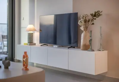 a living room with a television on a white cabinet at Hills Parkhouse - Pool Gym Parks Mall and Burj Khalifa View in Dubai