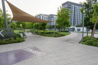 a park with a bench and trees and buildings at Hills Parkhouse - Pool Gym Parks Mall and Burj Khalifa View in Dubai
