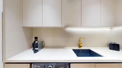 a kitchen with white cabinets and a sink at Dusk By Binghatti - Dazzling Studio in JVC in Dubai