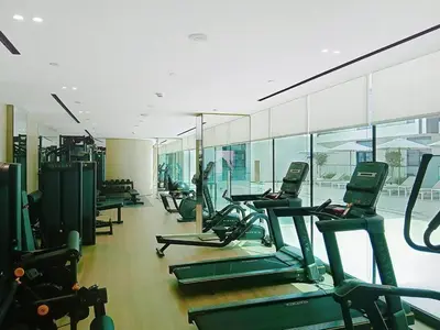 a gym with rows of treadmills and elliptical machines at Dusk By Binghatti - Dazzling Studio in JVC in Dubai